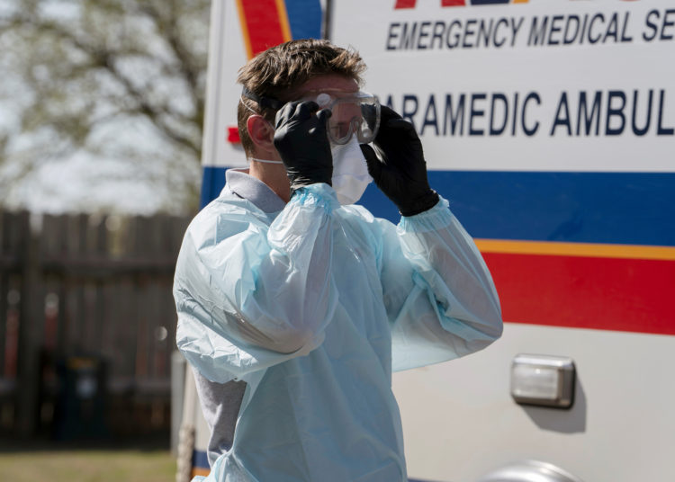 REACT EMS paramedic Brian Myers dons protective gear to transport a potential coronavirus disease (COVID-19) patient in Shawnee, Oklahoma, U.S. March 26, 2020. REUTERS/Nick Oxford
