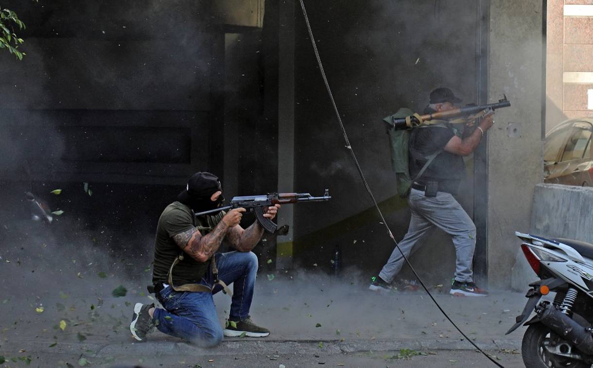 Combatientes chiíes de los movimientos terroristas Hezbolá y Amal apuntan con (de izquierda a derecha) un rifle de asalto Kalashnikov y un lanzagranadas propulsado por cohetes en medio de enfrentamientos en la zona de Tayouneh, en el suburbio del sur de la capital Beirut, el 14 de octubre de 2021 (IBRAHIM AMRO / AFP)