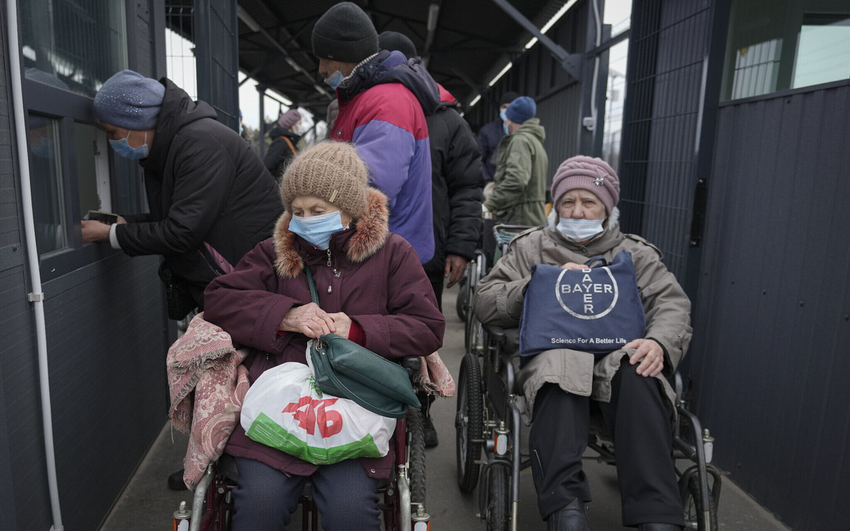 Personas esperan para cruzar desde las zonas controladas por el gobierno ucraniano al territorio controlado por los separatistas prorrusos en Stanytsia Luhanska, el único punto de cruce abierto diariamente, en la región de Luhansk, en el este de Ucrania, el 22 de febrero de 2022. (AP Photo/Vadim Ghirda)