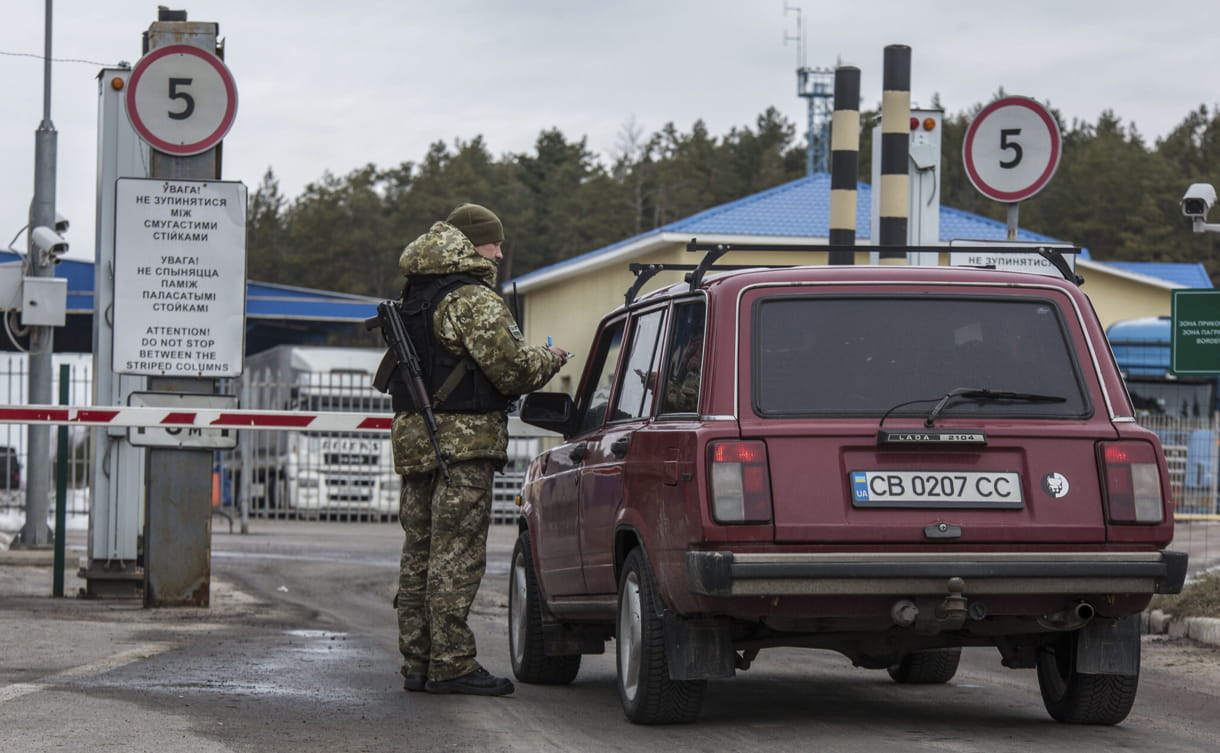 Un oficial de la guardia fronteriza ucraniana comprueba un coche en el puesto de control de la frontera estatal ucraniana de Novi Yarylovychi, Ucrania, el lunes 21 de febrero de 2022. (AP/Oleksandr Ratushniak)