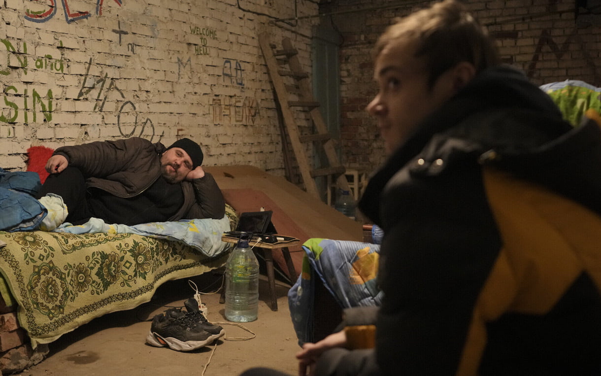 Personas tumbadas en camas improvisadas en un refugio en el sótano de un edificio de apartamentos durante el bombardeo de una central eléctrica y de calefacción en Shchastya, en la región de Luhansk, este de Ucrania, el 22 de febrero de 2022. (AP Photo/Vadim Ghirda)