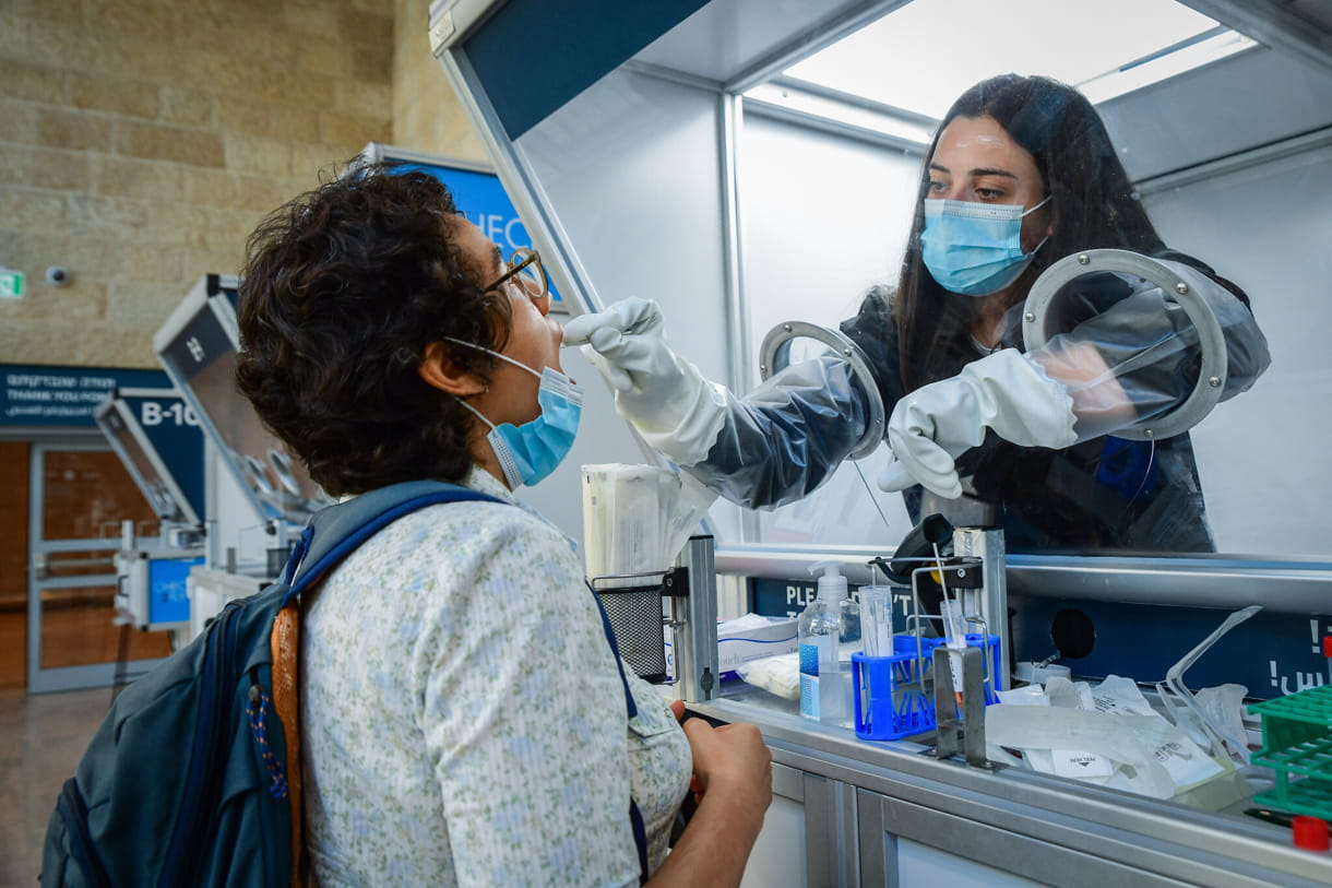 Un técnico médico realiza la prueba de COVID-19 a un viajero en el aeropuerto Ben Gurion, el 30 de junio de 2021. (Avshalom Sassoni/Flash90)