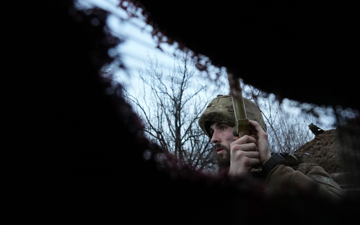 Un soldado ucraniano escucha fuego de artillería en una trinchera cerca de la línea de separación entre el territorio controlado por Ucrania y el territorio controlado por los rebeldes cerca de Zolote, Ucrania, el sábado 19 de febrero de 2022. (AP/Evgeniy Maloletka)