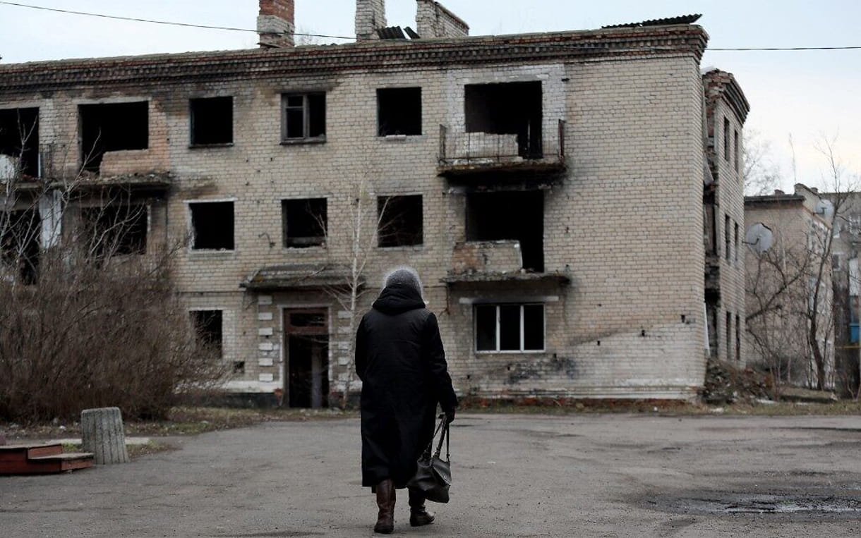 Una mujer pasa por delante de un viejo edificio destruido en la pequeña ciudad de Krasnogorivka, en la región de Donetsk, el 22 de febrero de 2022. (Aleksey Filippov/AFP)