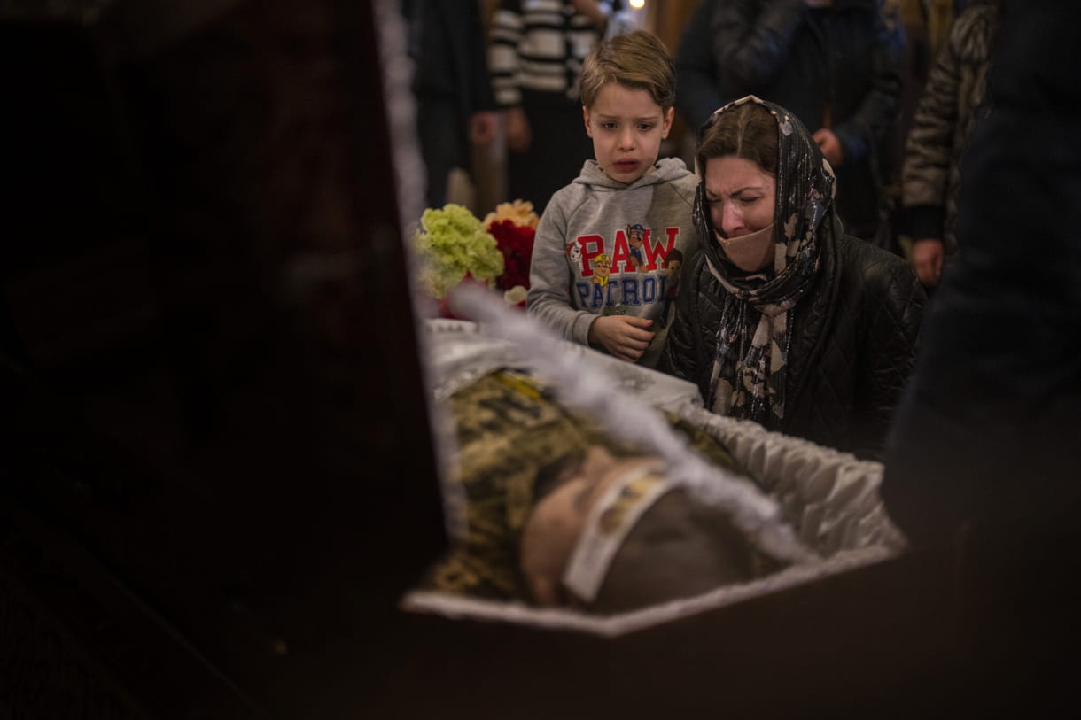 Una mujer y un niño reaccionan junto al cuerpo del capitán del ejército ucraniano Anton Sydorov, de 35 años, asesinado en el este de Ucrania, durante su funeral, en Kiev, Ucrania, el 22 de febrero de 2022. (AP Photo/Emilio Morenatti)