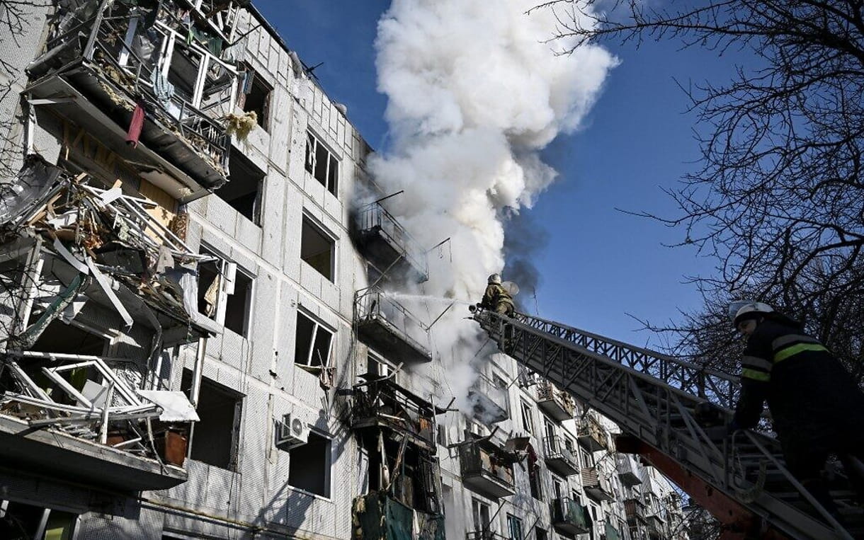 Los bomberos trabajan en el incendio de un edificio tras los bombardeos en la ciudad de Chuguiv, en el este de Ucrania, el 24 de febrero de 2022. (Aris Messinis/AFP)