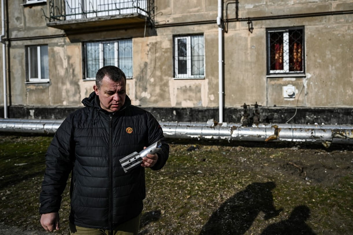 Un hombre sostiene los restos de un mortero que explotó frente a un edificio en la localidad de Schastia, cerca de la ciudad de Lugansk, en el este de Ucrania, el 22 de febrero de 2022 (Aris Messinis / AFP)