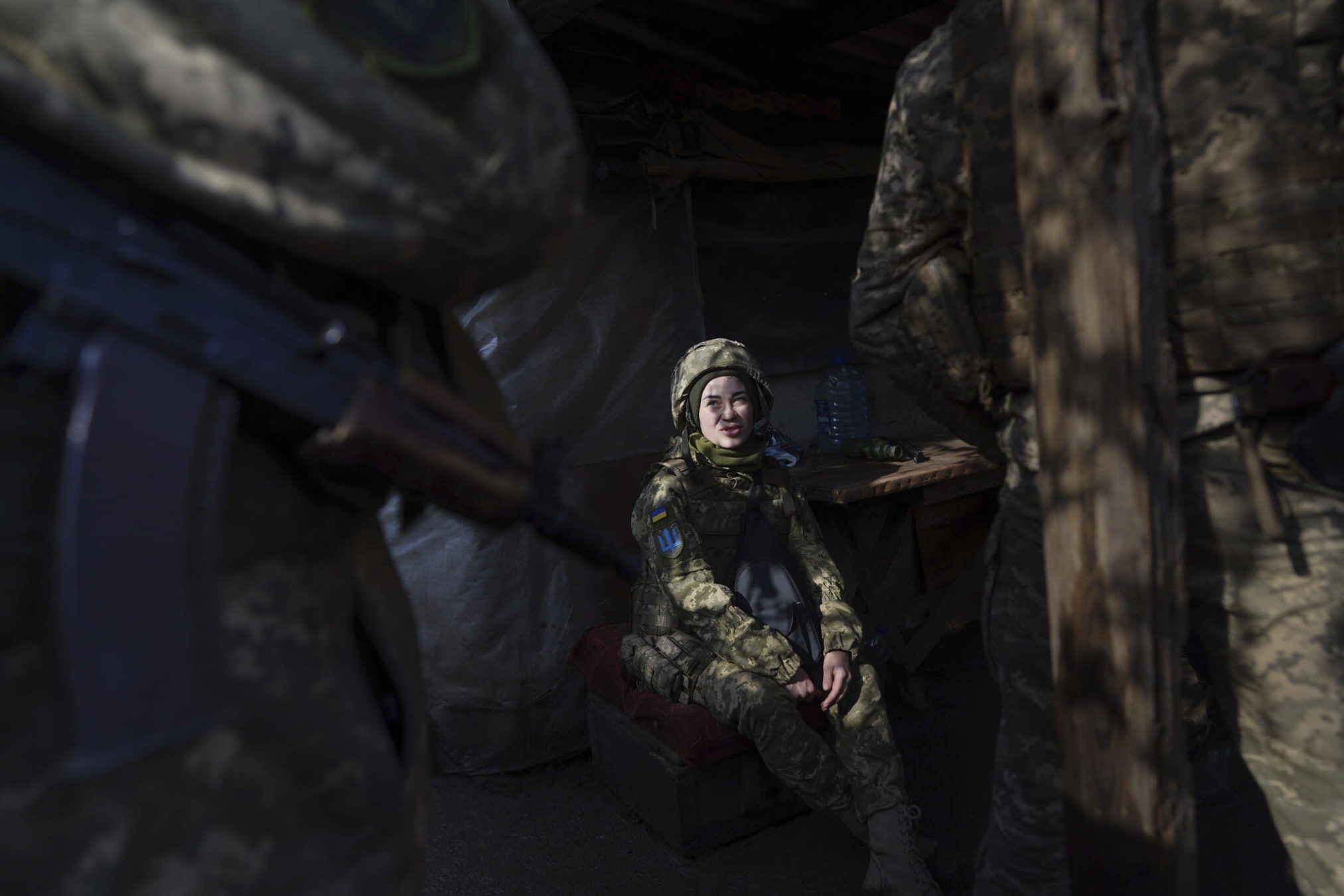 Una soldado ucraniana habla con sus compañeros sentada en un refugio en la línea de separación entre el territorio controlado por Ucrania y el territorio controlado por los rebeldes cerca de Svitlodarsk, en el este de Ucrania, el miércoles 23 de febrero de 2022. (AP Photo/Evgeniy Maloletka)