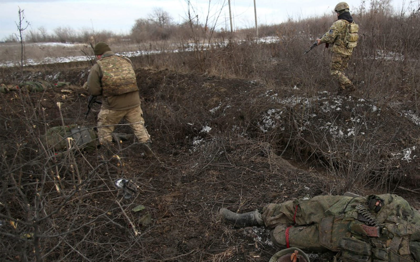 Tropas ucranianas pasan junto a un cadáver, tras los combates contra las fuerzas rusas y los separatistas respaldados por Rusia, cerca del pueblo de Zolote, en la región de Lugansk, el 6 de marzo de 2022. (Anatolii Stepanov/AFP)