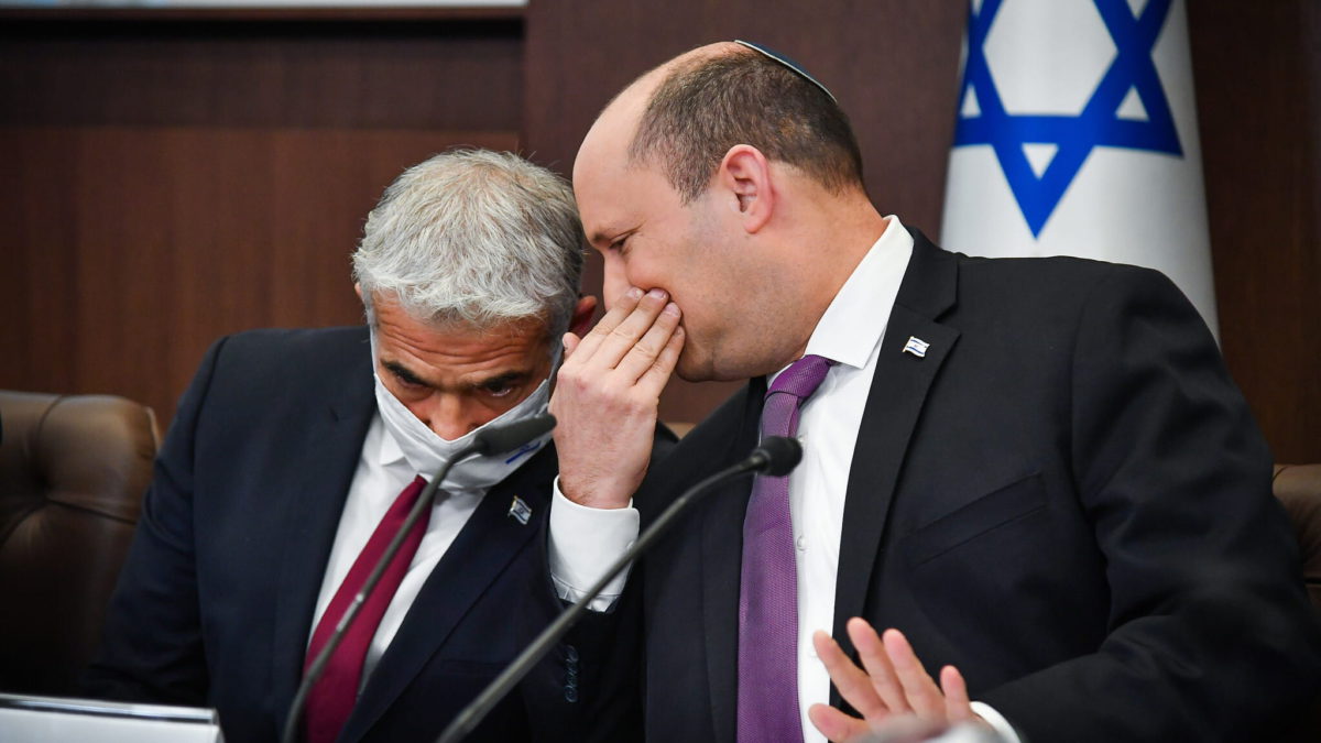 El primer ministro Naftali Bennett habla con el ministro de Asuntos Exteriores Yair Lapid durante una reunión del gabinete en la Oficina del primer ministro en Jerusalén, el 27 de febrero de 2022. (Yoav Ari Dudkevitch/Pool)