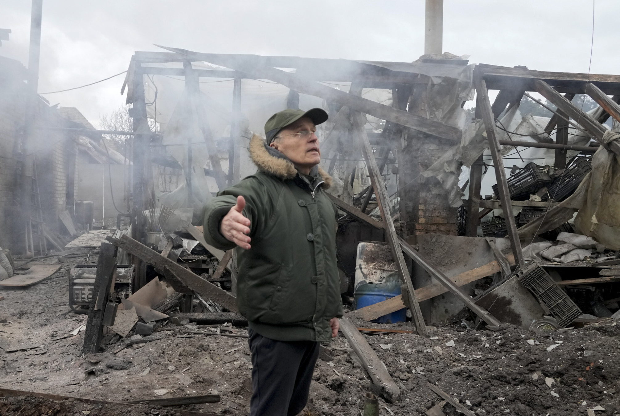 Un hombre abre los brazos mientras se encuentra cerca de una casa destruida por los bombardeos de la artillería rusa, en el pueblo de Horenka, cerca de Kiev, Ucrania, el 6 de marzo de 2022. (Efrem Lukatsky/AP)