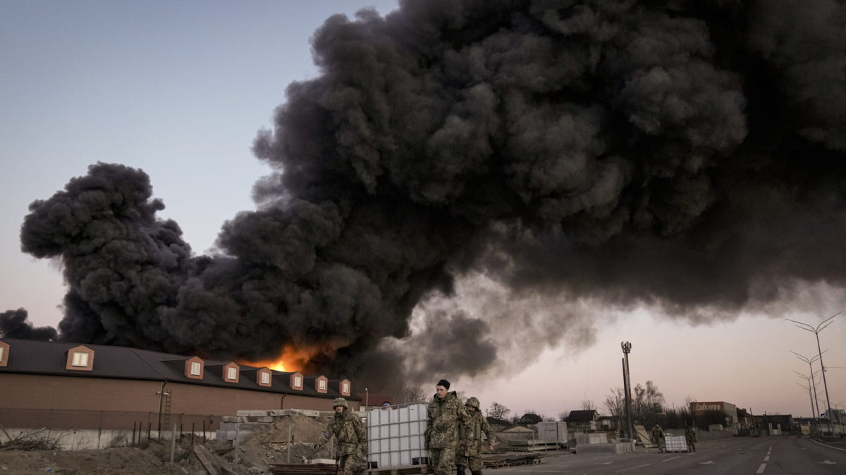 Militares ucranianos transportan contenedores envueltos en llamas en un almacén tras un bombardeo en las afueras de Kiev, Ucrania, el jueves 17 de marzo de 2022. (AP Photo/Vadim Ghirda)