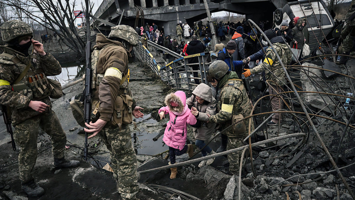 La gente cruza un puente destruido mientras evacua la ciudad de Irpin, al noroeste de Kiev, durante un intenso bombardeo el 5 de marzo de 2022, 10 días después de que Rusia lanzara una invasión militar en Ucrania. (Aris Messinis/AFP)