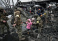 La gente cruza un puente destruido mientras evacua la ciudad de Irpin, al noroeste de Kiev, durante un intenso bombardeo el 5 de marzo de 2022, 10 días después de que Rusia lanzara una invasión militar en Ucrania. (Aris Messinis/AFP)