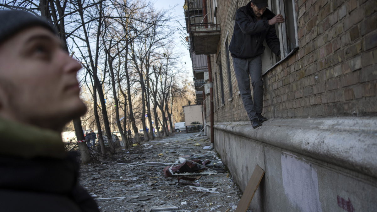 Vecinos intentan limpiar los daños de los apartamentos tras un bombardeo, en Kiev, Ucrania, el 23 de marzo de 2022. (Rodrigo Abd/AP)