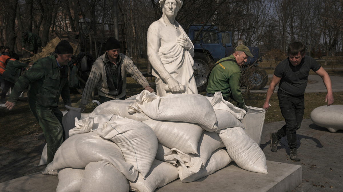 Trabajadores municipales cubren la estatua del poeta y filósofo italiano Dante Alighieri con sacos de arena para protegerla de posibles daños por los bombardeos, en Kiev, Ucrania, el 23 de marzo de 2022. (Vadim Ghirda/AP)