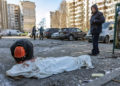 Una persona llora junto a un cuerpo cubierto cerca de un edificio residencial que fue alcanzado por los restos de un cohete derribado en Kiev el 17 de marzo de 2022. (Fadel Senna/AFP)