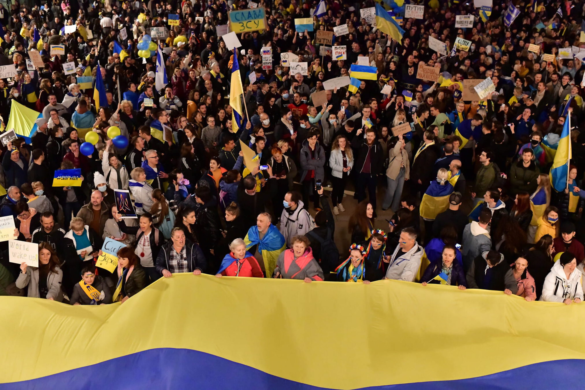 Manifestantes llevan pancartas y banderas durante una marcha de protesta contra la invasión rusa a Ucrania, en Tel Aviv, el 26 de febrero de 2022. (Tomer Neuberg/Flash90)