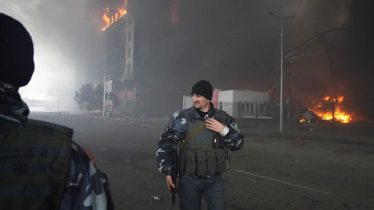 Militares ucranianos caminan mientras el fuego y el humo se elevan sobre un edificio tras un bombardeo en Kiev, Ucrania, el jueves 3 de marzo de 2022. (AP/Efrem Lukatsky)