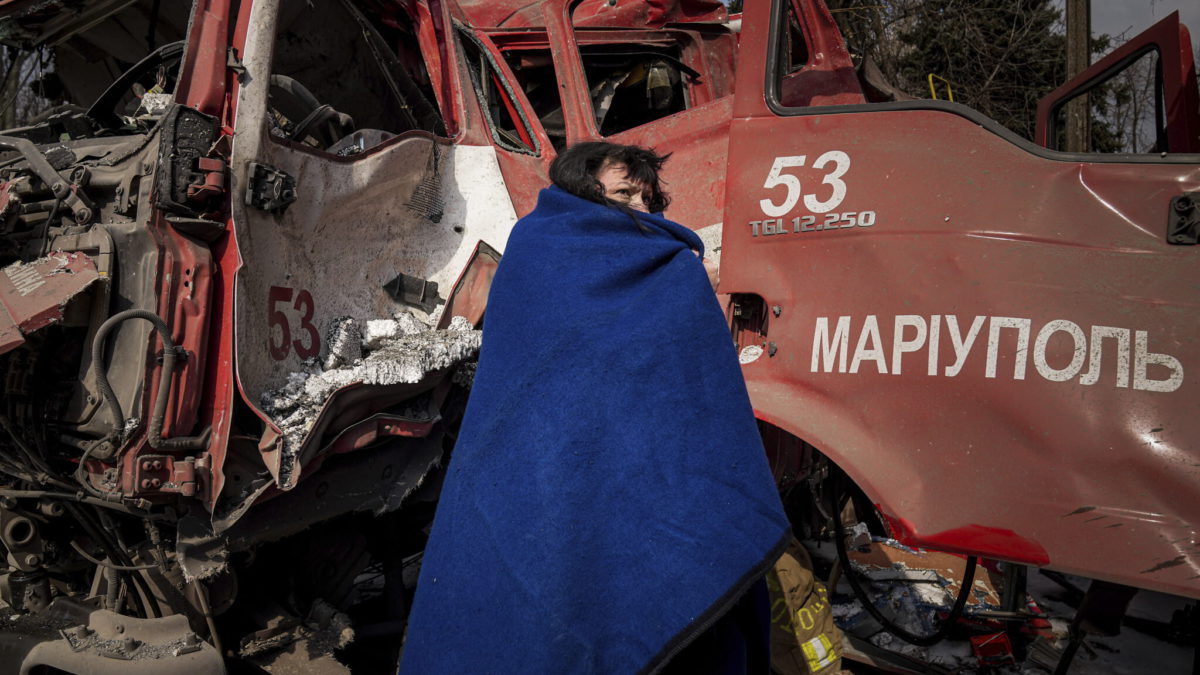 Una mujer se cubre con una manta cerca de un camión de bomberos dañado tras un bombardeo en Mariupol, Ucrania, el jueves 10 de marzo de 2022. (AP Photo/Evgeniy Maloletka)