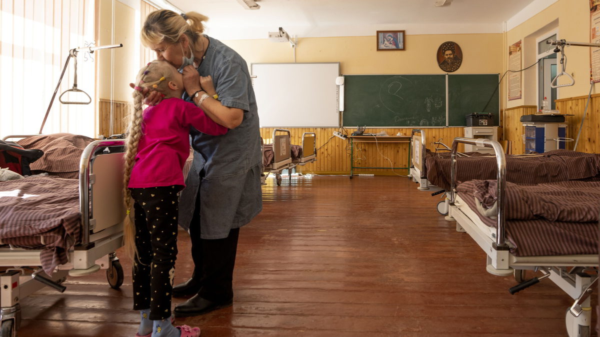Nadia besa a su nieta de 10 años, Zlata Moiseinko, que padece una enfermedad cardíaca crónica, mientras recibe tratamiento en una escuela convertida en hospital de campaña en Mostyska, al oeste de Ucrania, el 24 de marzo de 2022. (AP Photo/Nariman El-Mofty)