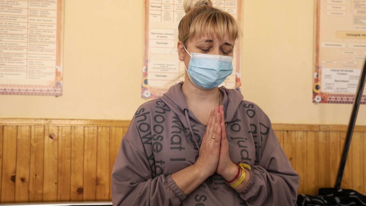 Natalia Moiseinko, de 45 años, habla de su hija Zlata Moiseinko, de 10 años, que padece una enfermedad cardíaca crónica, mientras recibe tratamiento en una escuela convertida en hospital de campaña, en Mostyska, Ucrania occidental, el 24 de marzo de 2022. (AP Photo/Nariman El-Mofty)