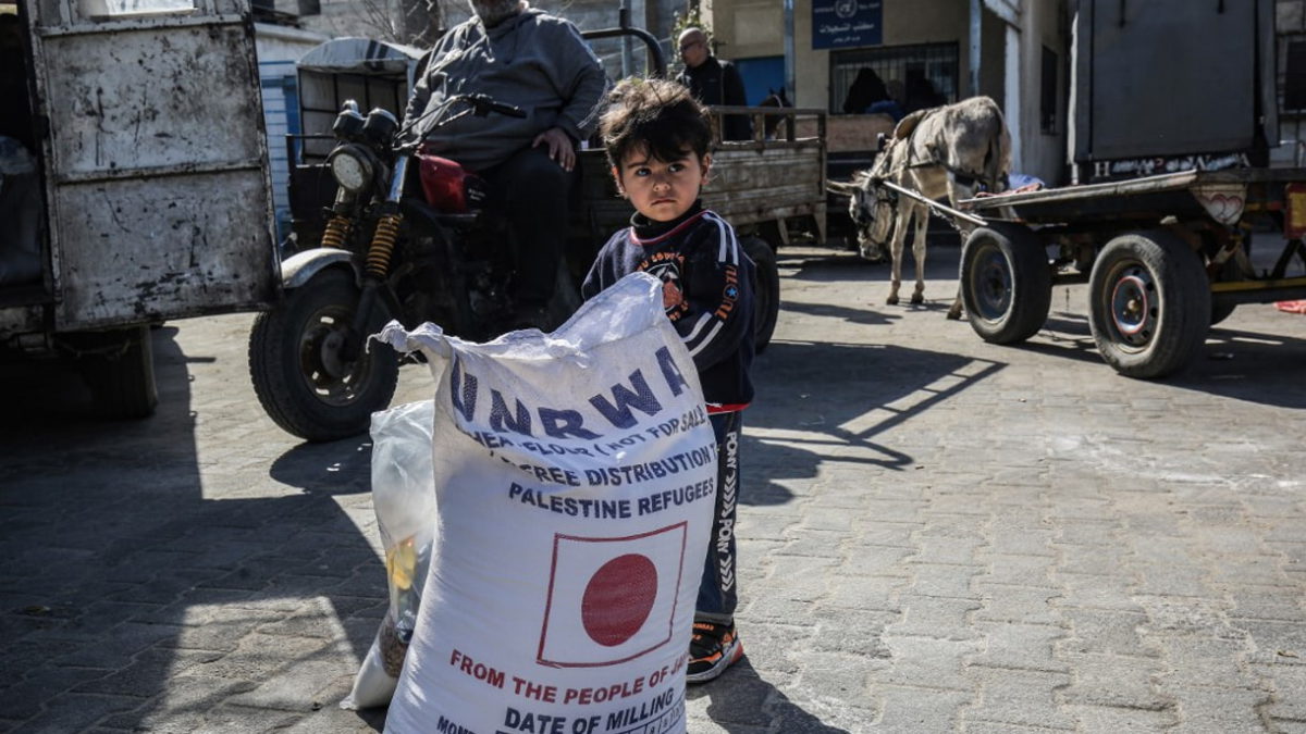 Un niño junto a un saco de harina, mientras la gente acude a recibir ayuda alimentaria de un centro de distribución del Organismo de Obras Públicas y Socorro de las Naciones Unidas (UNRWA) en Khan Younis, en la Franja de Gaza, el 2 de febrero de 2020. (SAID KHATIB/ AFP/ Archivo)