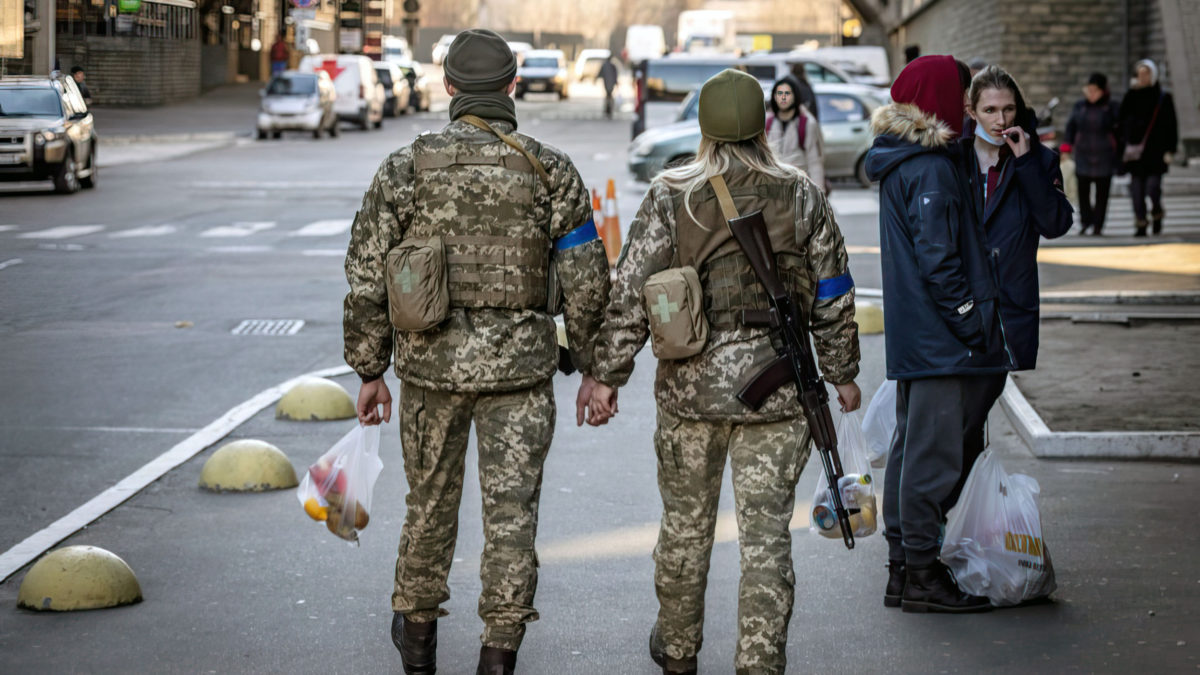 Una pareja de soldados ucranianos se toma de la mano mientras caminan por la calle en Kiev, el 18 de marzo de 2022 (FADEL SENNA / AFP)