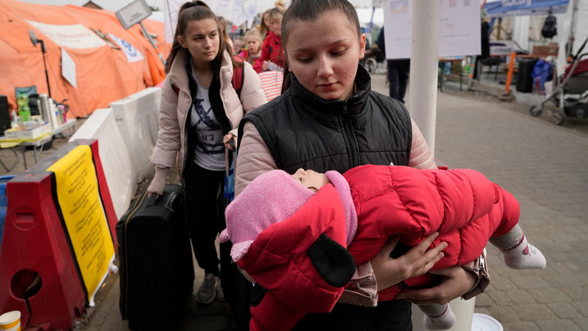 Una refugiada lleva un bebé tras huir de la guerra de la vecina Ucrania en el paso fronterizo de Medyka, al sureste de Polonia, el 29 de marzo de 2022. (AP Photo/Sergei Grits)