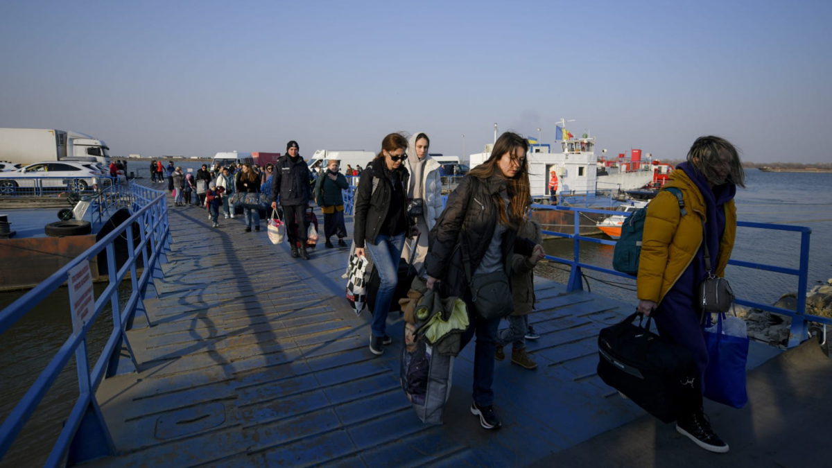 Refugiados que huyen de la guerra de la vecina Ucrania caminan después de cruzar la frontera en ferry en el paso fronterizo de Isaccea-Orlivka en Rumanía, el jueves 24 de marzo de 2022. (AP Photo/Andreea Alexandru)