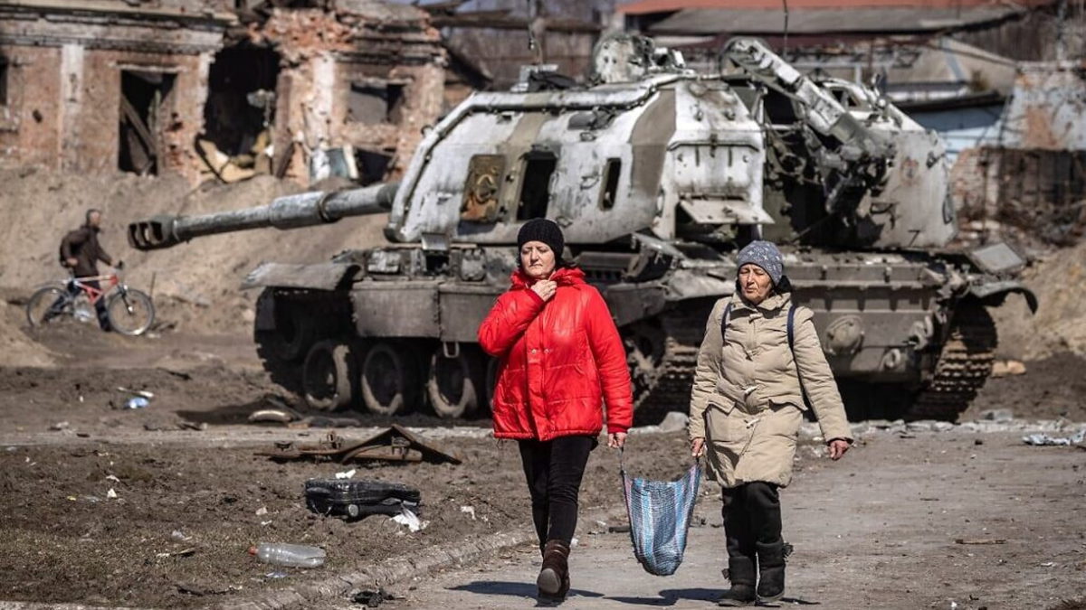 Los residentes pasan por delante de un tanque ruso dañado en la ciudad nororiental de Trostyanets, el 29 de marzo de 2022. (FADEL SENNA / AFP)
