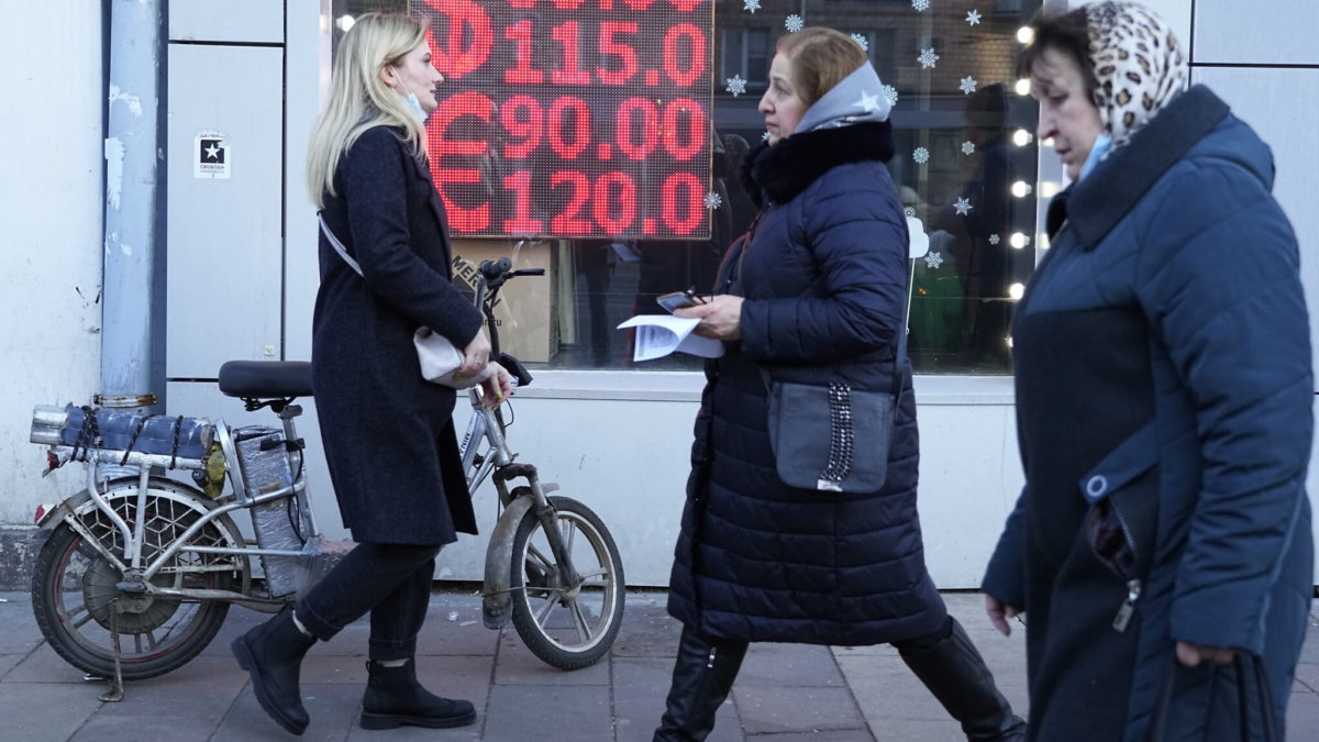 La gente pasa por delante de una pantalla de una oficina de cambio de moneda que muestra los tipos de cambio del dólar estadounidense y el euro a los rublos rusos en el centro de Moscú, Rusia, el lunes 28 de febrero de 2022. (AP/Pavel Golovkin)