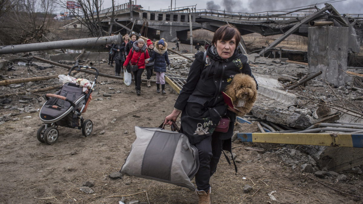 Personas cruzan un camino improvisado bajo un puente destruido mientras huyen de la ciudad de Irpin, Ucrania, el 6 de marzo de 2022. (Oleksandr Ratushniak/AP)