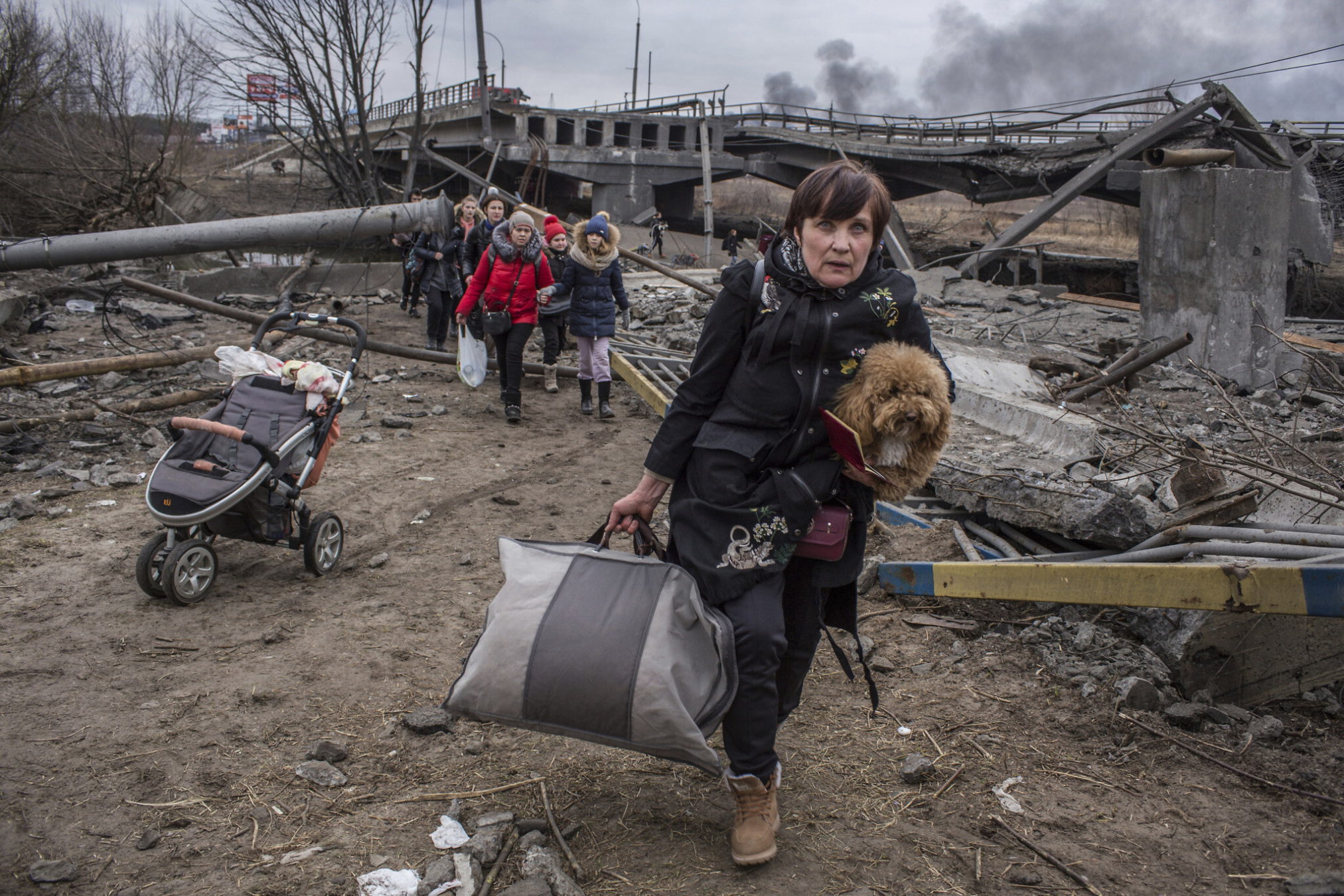 Personas cruzan un camino improvisado bajo un puente destruido mientras huyen de la ciudad de Irpin, Ucrania, el 6 de marzo de 2022. (Oleksandr Ratushniak/AP)