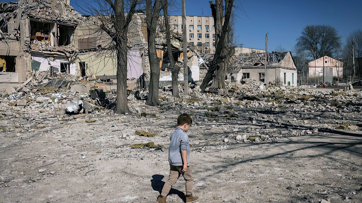 Un niño camina frente a una escuela dañada en la ciudad de Zhytomyr, en el norte de Ucrania, el 23 de marzo de 2022. (Fadel Senna/AFP)