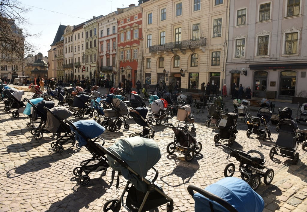 En esta foto tomada el 18 de marzo de 2022, se ven 109 cochecitos y cestas de bebé vacías colocadas frente al ayuntamiento de Lviv durante una acción para destacar el número de niños muertos en la actual invasión rusa de Ucrania. (Yuriy Dyachyshyn / AFP)