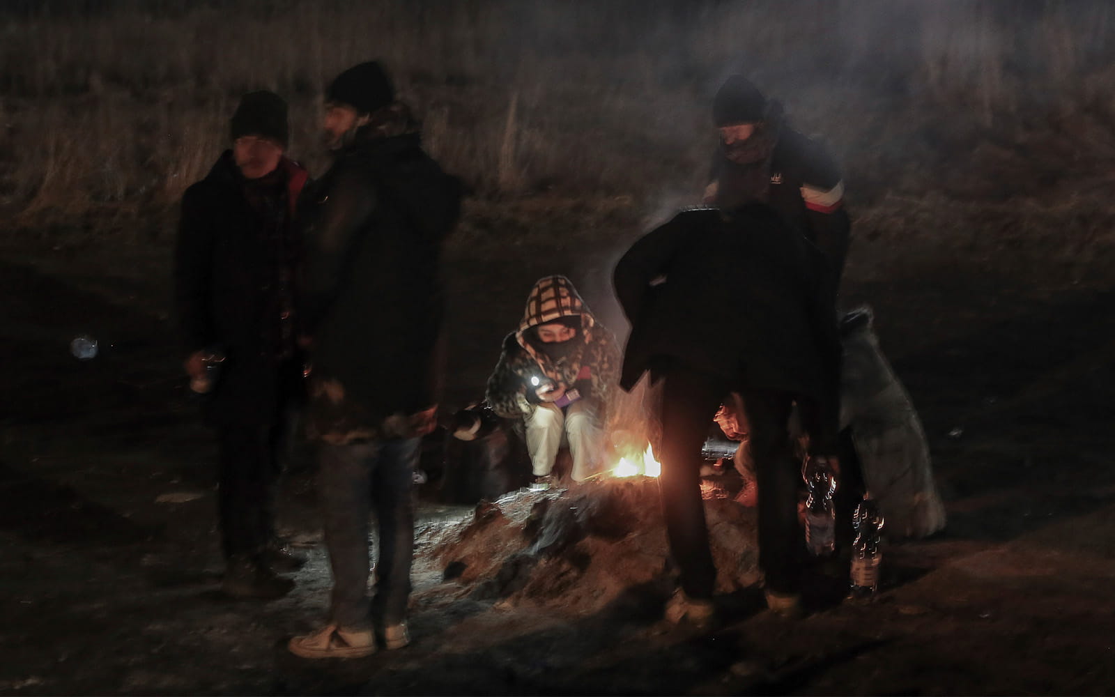 Estudiantes se reúnen alrededor de una hoguera para calentarse en el paso fronterizo de Medyka tras huir de Ucrania, en Polonia, el 28 de febrero de 2022. (AP Photo/Visar Kryeziu)