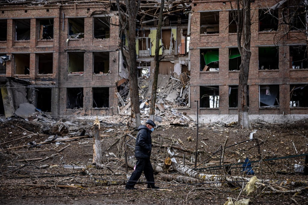 Un hombre camina frente a un edificio destruido tras un ataque con misiles rusos en la ciudad de Vasylkiv, cerca de Kiev, el 27 de febrero de 2022 (Dimitar Dilkoff/AFP)
