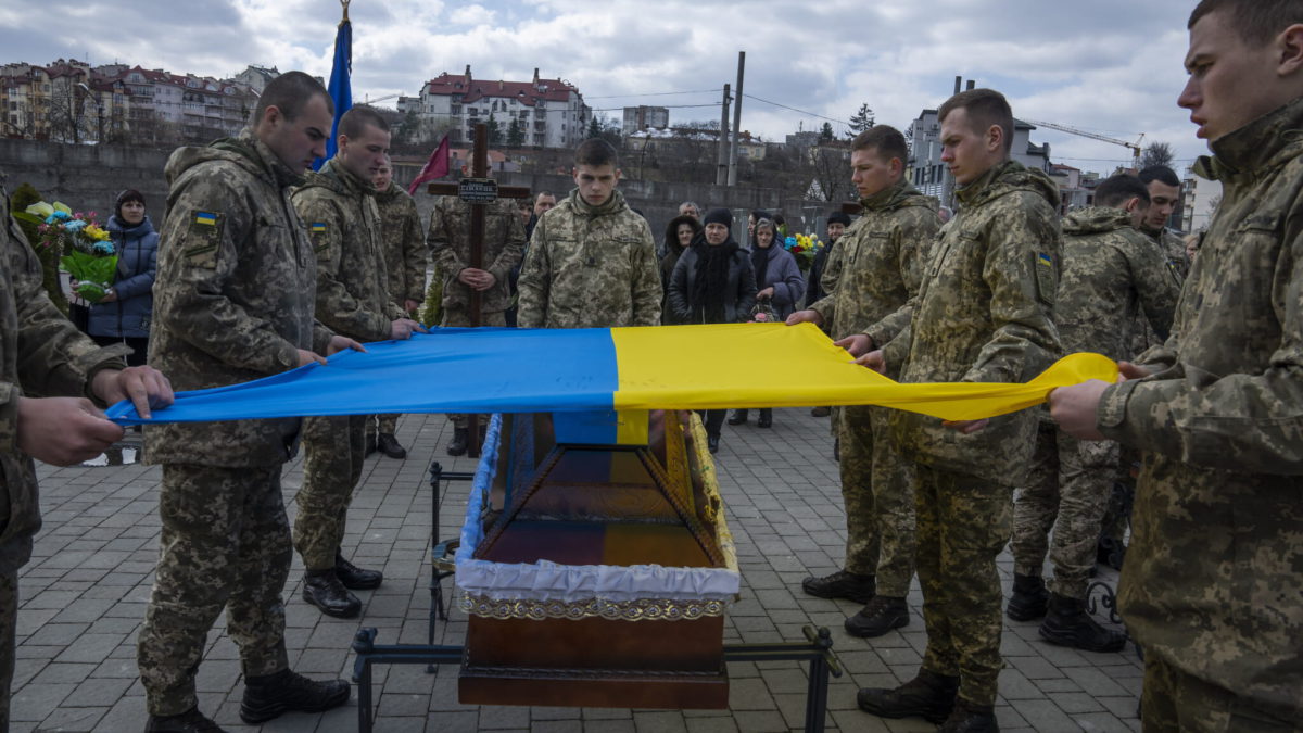Unos soldados colocan la bandera ucraniana sobre el ataúd del soldado de 41 años Simakov Oleksandr, durante su ceremonia fúnebre, después de haber muerto en combate, en el cementerio de Lychakiv, en Lviv, al oeste de Ucrania, el lunes 4 de abril de 2022. (AP Photo/Nariman El-Mofty)