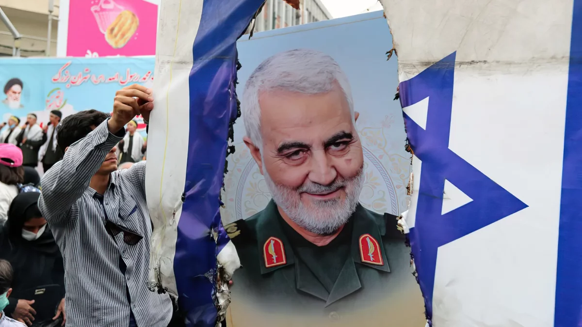 Los iraníes se preparan para prender fuego a una bandera israelí junto a una foto del difunto general iraní Qasem Soleimani durante una manifestación para celebrar el día de al-Quds (Jerusalén) en Teherán, el 29 de abril de 2022 (AFP)