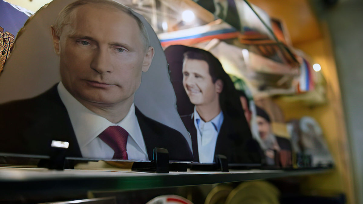 Una foto tomada el 17 de marzo de 2018 muestra los retratos del presidente ruso Vladimir Putin, el presidente sirio Bashar al-Assad y el líder libanés de Hezbolá, Hassan Nasrallah, en una joyería de la ciudad de Alepo, en el norte de Siria. (Foto AFP/ George Ourfalian)