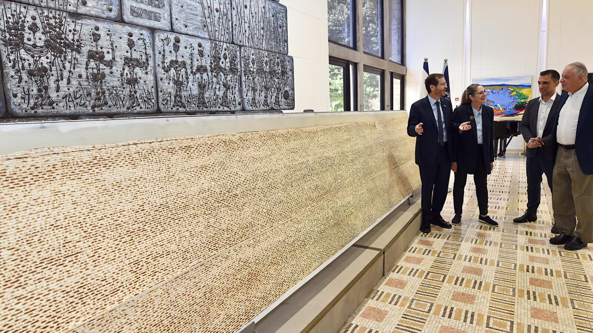 El presidente Herzog y la primera dama Michal Herzog presentaron la matzá más grande de Israel en la Casa del presidente en Jerusalén, el 10 de abril de 2022. (Haim Zach/GPO)