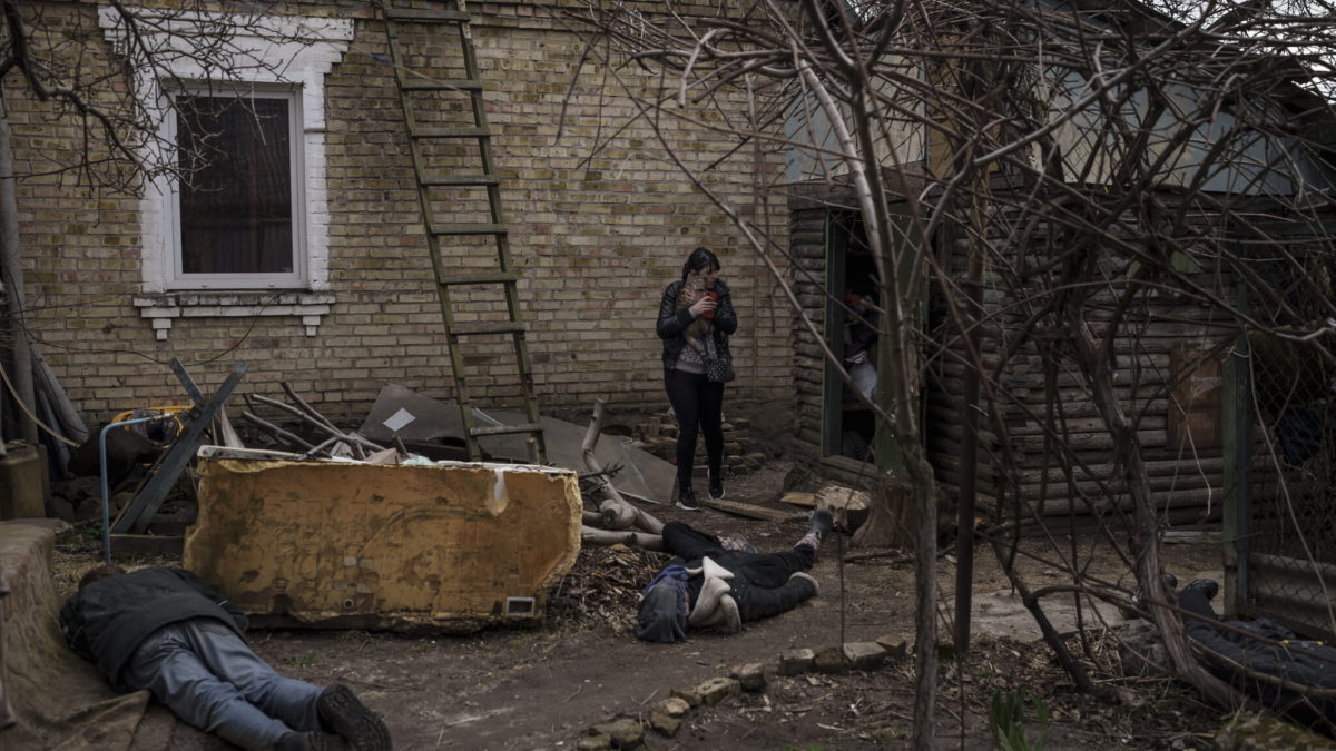 Ira Gavriluk sostiene a su gato mientras camina entre los cuerpos de su marido, su hermano y otro hombre, que fueron asesinados fuera de su casa en Bucha, en las afueras de Kiev, Ucrania, el lunes 4 de abril de 2022. (AP Photo/Felipe Dana)