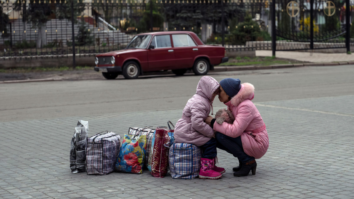 Una madre abraza a su hija mientras esperan un autobús para huir de la ciudad de Sloviansk, en el distrito de Donetsk, para viajar a Rivne, en el oeste de Ucrania, el sábado 16 de abril de 2022. (AP Photo/Petros Giannakouris)