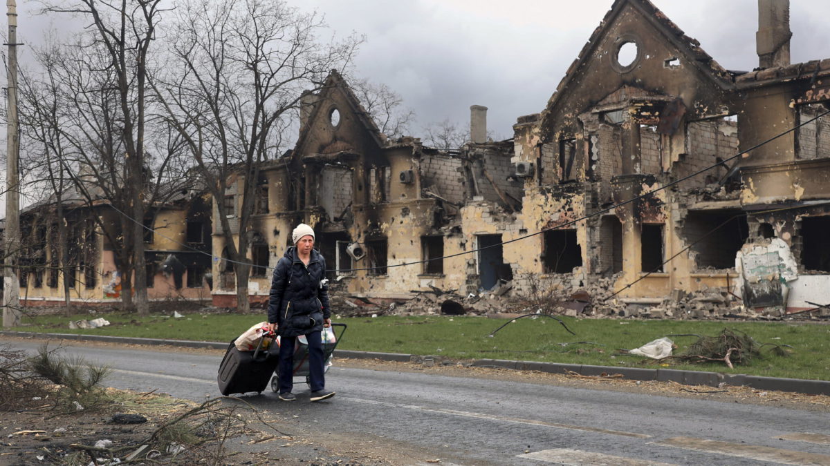 Una mujer tira de sus bolsas frente a las casas dañadas durante los combates en Mariupol, en el territorio que ahora está bajo el control del Gobierno de la República Popular de Donetsk, al este de Mariupol, Ucrania, el 8 de abril de 2022. (AP Photo/Alexei Alexandrov)