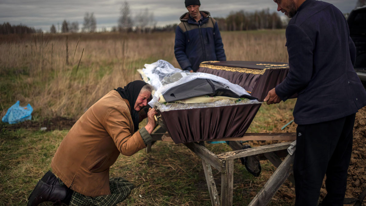 Nadiya Trubchaninova, de 70 años, llora mientras sostiene el féretro de su hijo Vadym, de 48 años, asesinado por soldados rusos el pasado 30 de marzo en Bucha, durante su funeral en el cementerio de Mykulychi, en las afueras de Kiev, Ucrania, el sábado 16 de abril de 2022 (AP Photo/Rodrigo Abd)
