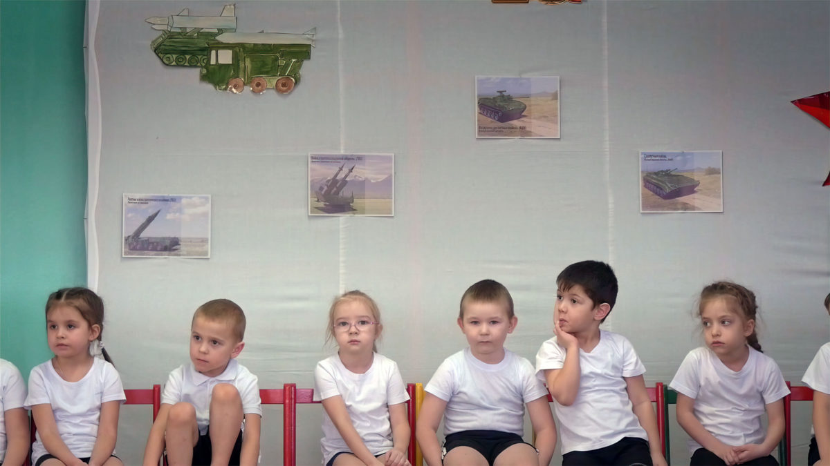 Alumnos de guardería cantan canciones militares rusas en un aula decorada con imágenes de armas en Yelnya, Rusia, en el documental de Dmitry Bogolyubov, “Town of Glory”. (Cortesía de First Hand Films)