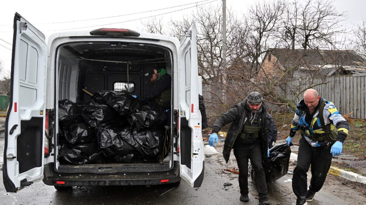 Trabajadores municipales transportan el cuerpo de un civil en la ciudad de Bucha, no muy lejos de la capital ucraniana, Kiev, el 3 de abril de 2022. (Sergei SUPINSKY / AFP)