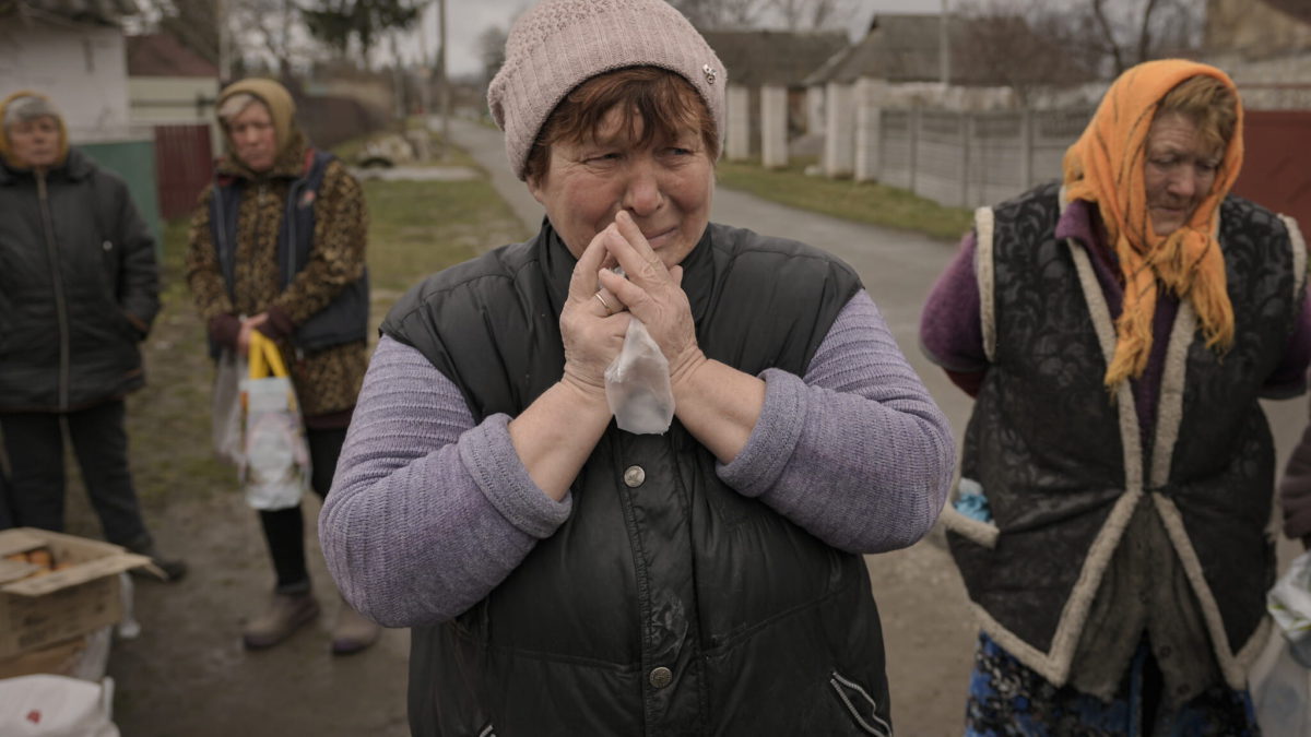 Una mujer llora mientras espera junto a otras personas la distribución de productos alimenticios en el pueblo de Motyzhyn, Ucrania, que hasta hace poco estaba bajo el control del ejército ruso, el domingo 3 de abril de 2022. (AP Photo/Vadim Ghirda)