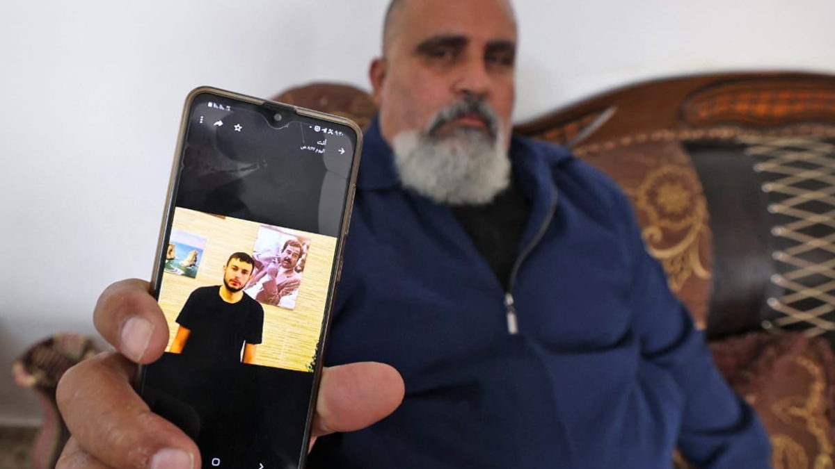 Un hombre palestino muestra una foto de su sobrino Raad Hazem, de 28 años, un terrorista palestino que mató a tres israelíes e hirió a varios otros en Tel Aviv la noche anterior, el 8 de abril de 2022 en la ciudad cisjordana de Jenín. (JAAFAR ASHTIYEH / AFP)